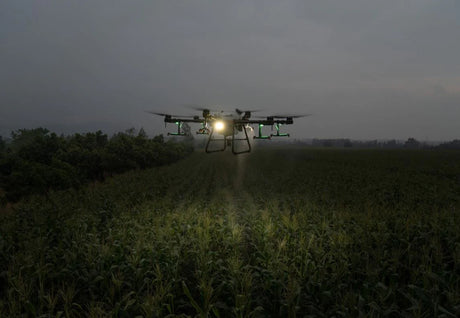 DJI Agras T30 Agriculture Drone flying over a field at night with lights